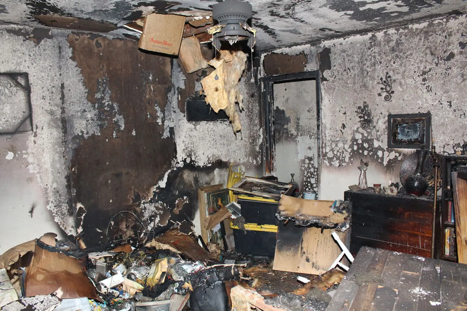 Severely fire-damaged room with debris and burnt walls.