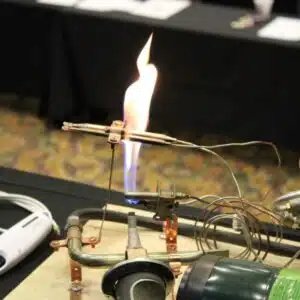 Person demonstrating gas burner experiment at a science event.