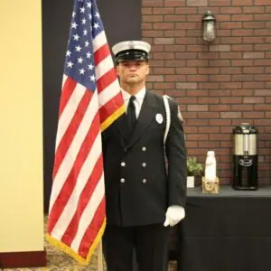 Firefighter holding American flag at indoor event.