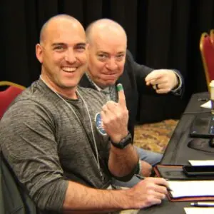 Two men smiling in a conference room.