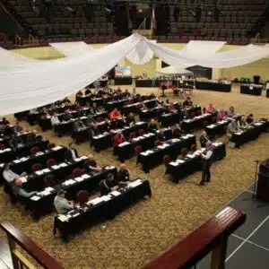 Business conference with attendees seated in a large hall.