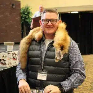 Man at event with fur shoulder wrap smiling