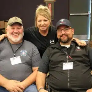 Three smiling people posing together at an event.