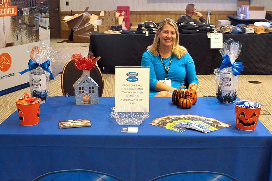 Woman at booth with gift baskets and Halloween decorations.