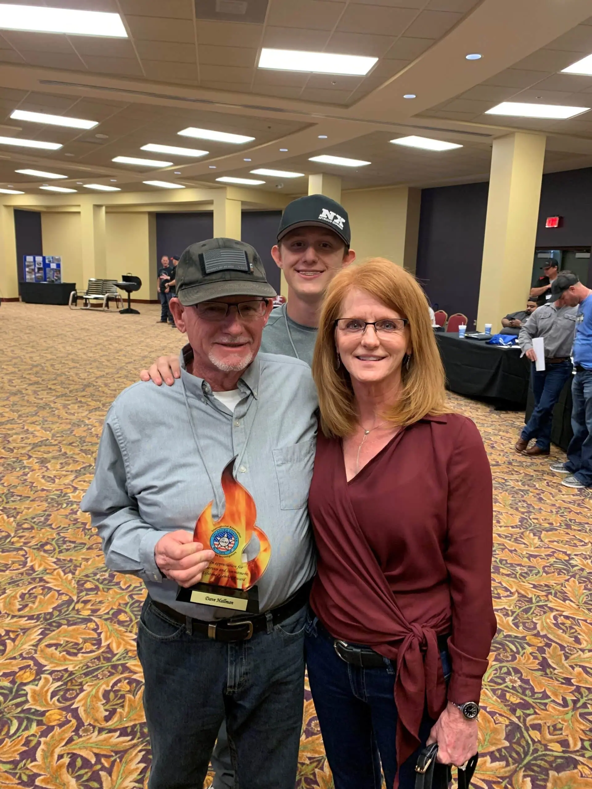 Man holding award with friends at indoor event.
